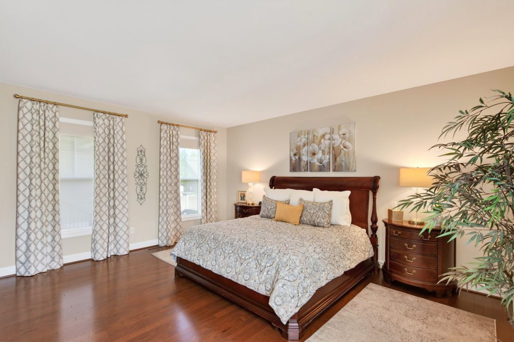Primary suite from the doorway, roller shades layered under stationary panels