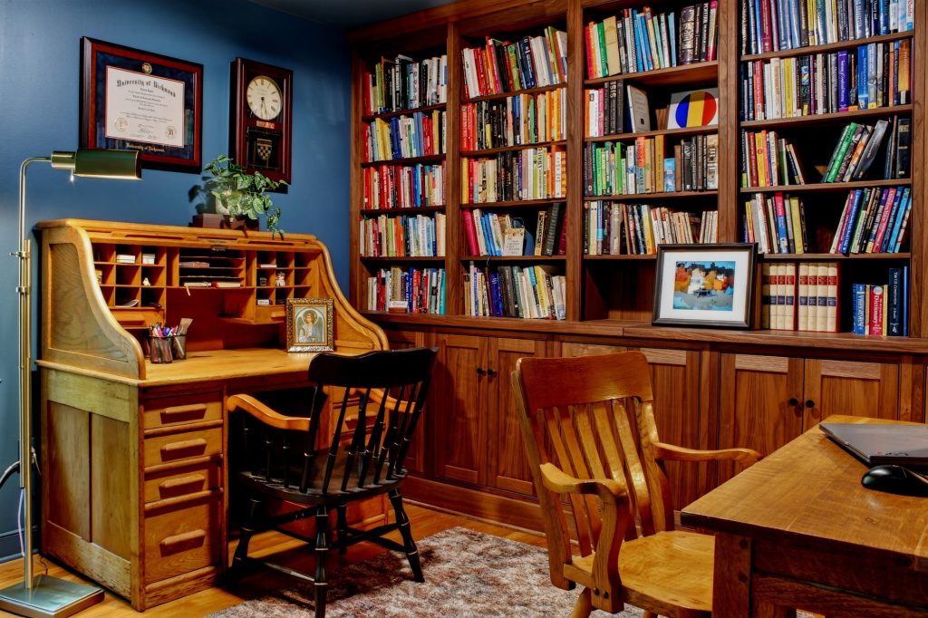 Study with a roll-top desk set against floor-to-ceiling bookcases