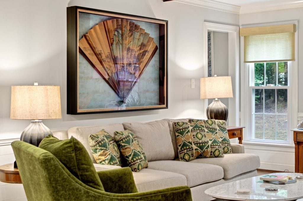 Living room with a fan-shaped artwork above the sofa and a pair of green armchairs