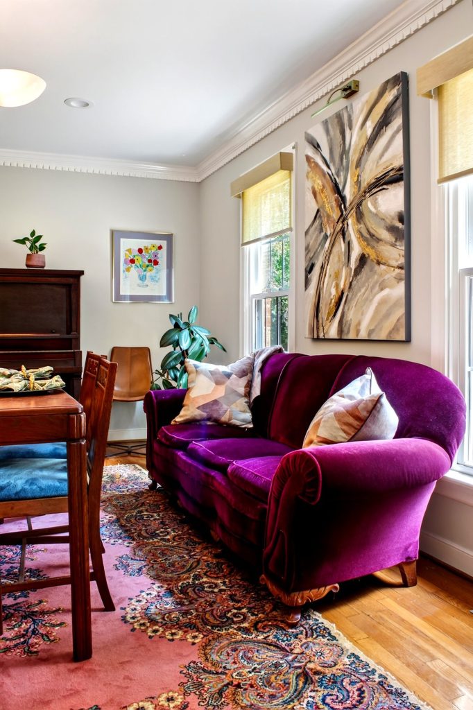 Living room corner with a purple velvet armchair and a patterned rug